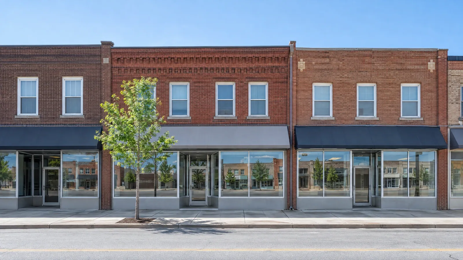 Two-storey brick commercial buildings with large ground-floor display windows along a quiet main street